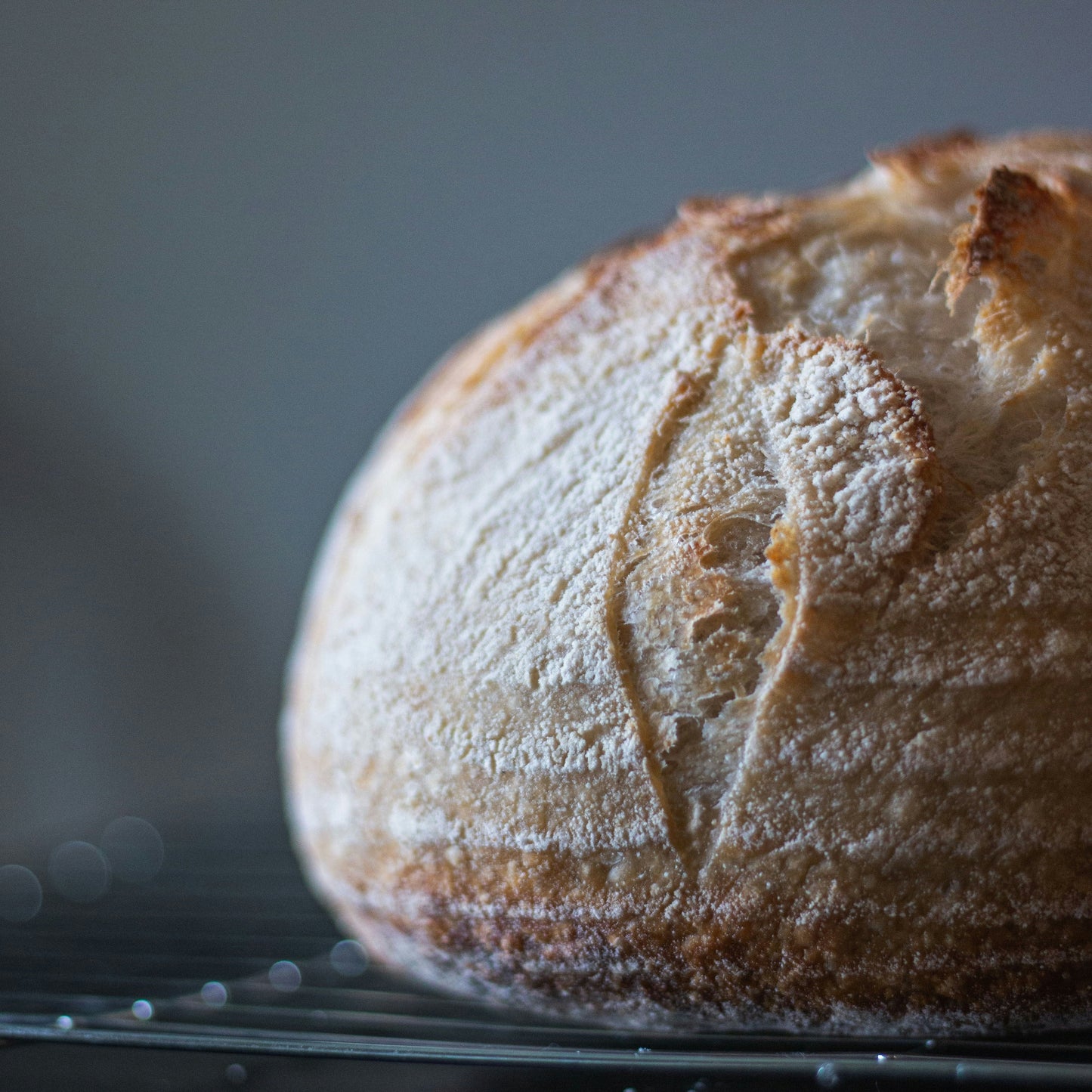 Loaf of bread on a cooling rack with a dark background
